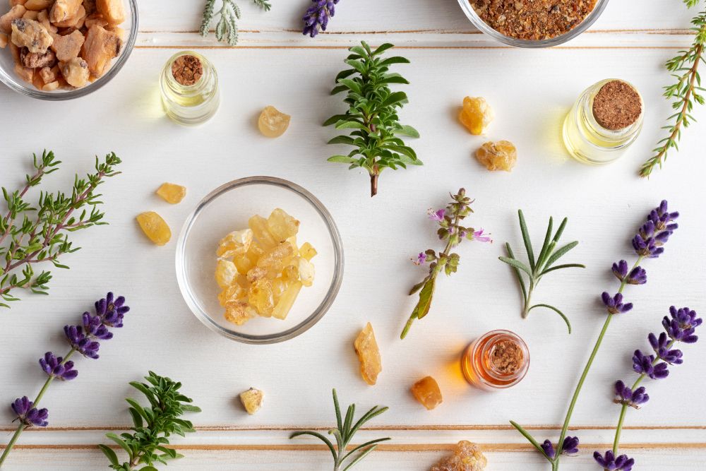 Buteleczki z olejkami eterycznymi otoczone świeżymi ziołami i kwiatami do aromaterapii