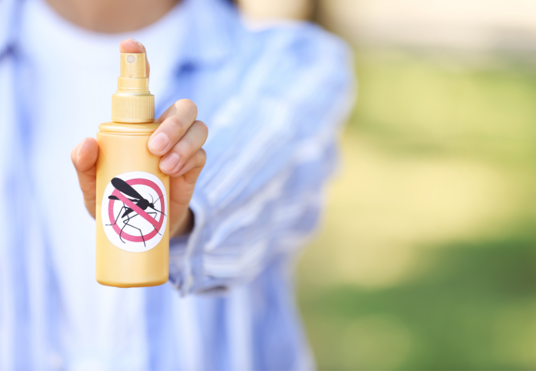 Osoba trzymająca spray odstraszający komary na zewnątrz.